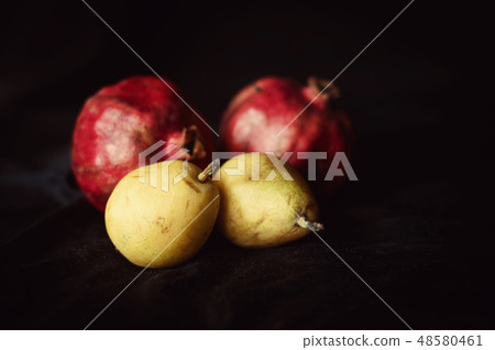 bright, ripe pomegranat and pear on black background bright, ripe pomegranat and pear on black background 48580461