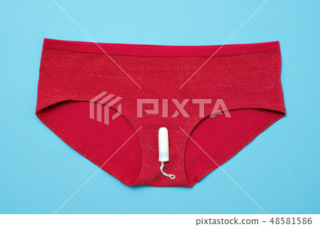 White tampon on red pants on colored background. 48581586