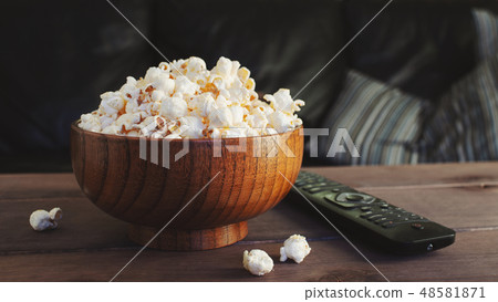 A wooden bowl of salted popcorn. 48581871
