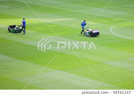 The lawnmower man mows the lawn in a stadium. The lawnmower man mows the lawn in a stadium. 48582187