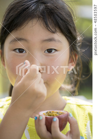 Girls eating passion fruit Girls eating passion fruit 48583597