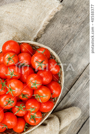 Red tomatoes in a wicker basket on an wooden table Red tomatoes in a wicker basket on an wooden table 48588377