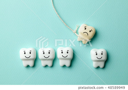 Healthy white teeth are smiling and the removal of the baby tooth with rope is sad on green mint Healthy white teeth are smiling and the removal of the baby tooth with rope is sad on green mint 48589949