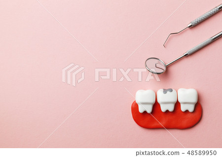 Healthy white teeth and tooth with caries on pink background  and dentist tools mirror, hook. Copy 48589950