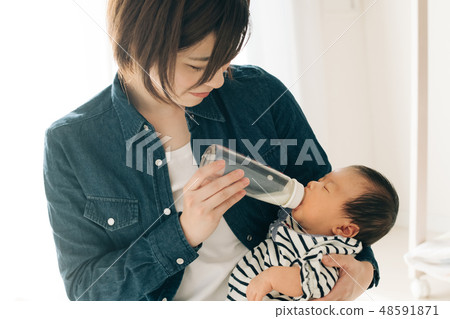 嬰孩護理育兒在媽媽和在一個哺乳瓶的飲用奶舉行 照片素材 圖片 圖庫