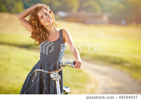 Sexy woman with vintage bike in a country road. Sexy woman with vintage bike in a country road. 48594937