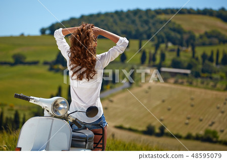 Young beautiful italian woman sitting on a italian scooter in tu 48595079