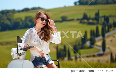 Young beautiful italian woman sitting on a italian scooter in tu 48595086