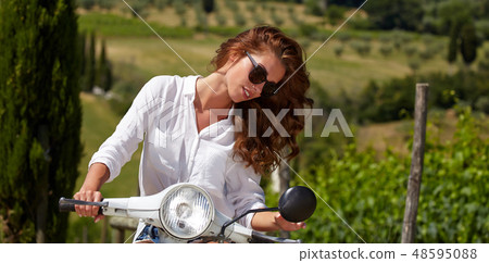 Young beautiful italian woman sitting on a italian scooter in tu 48595088
