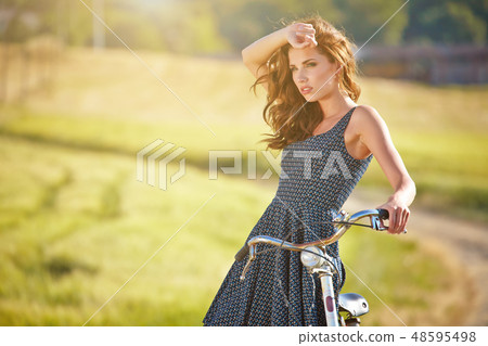 Sexy woman with vintage bike in a country road. 48595498