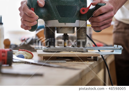 carpenter makes holes with a drill in wooden part carpenter makes holes with a drill in wooden part 48598005