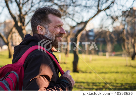 Mature man is walking in a park with a backpack   48598626