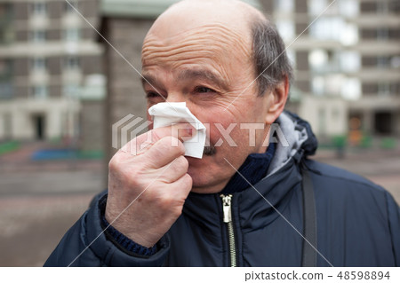 An elderly man d wipes his nose. An elderly man d wipes his nose. 48598894