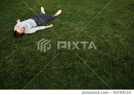 woman lays down on grass and rests 48599534