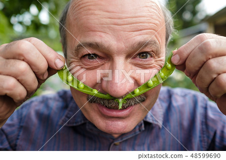 man holds a pea pod near his face like a mustache 48599690