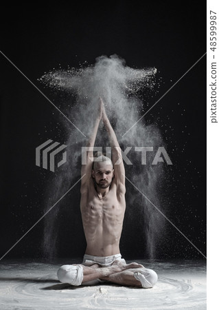 A yoga teacher sits in a sukhasana A yoga teacher sits in a sukhasana 48599987