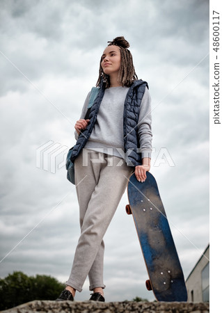 hipster girl with skate board standing with smile 48600117