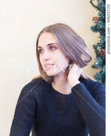 A beautiful young woman in pullover on background of Christmas lights A beautiful young woman in pullover on background of Christmas lights 48603720
