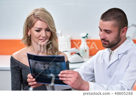 Caucasian male dentist explaining to female patient the x-ray 48605288