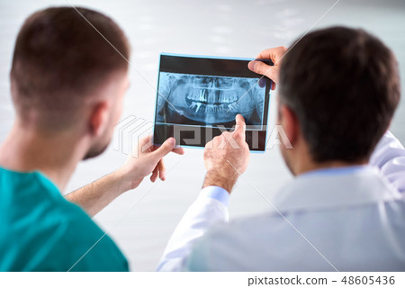 Two caucasian male dentists analyzing x-ray Two caucasian male dentists analyzing x-ray 48605436