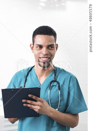 Men in a cyan colored dental coat taking notes 48605579