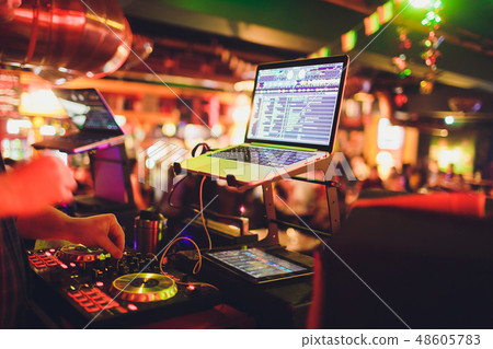 Hands of DJ mix tracks on digital turntable and software on laptop with professional mixing software Hands of DJ mix tracks on digital turntable and software on laptop with professional mixing software 48605783