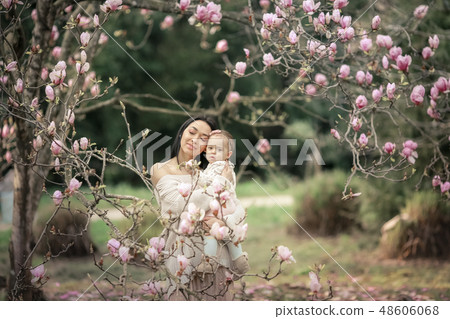 Young mother and little daughter in autumn park play with magnolia leaves. Happy weekend with family Young mother and little daughter in autumn park play with magnolia leaves. Happy weekend with family 48606068