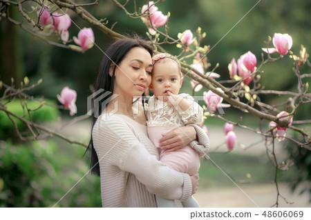 Young mother and little daughter in autumn park play with magnolia leaves. Happy weekend with family Young mother and little daughter in autumn park play with magnolia leaves. Happy weekend with family 48606069