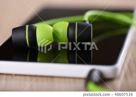 Smartphone and green earphones on the table 48607516
