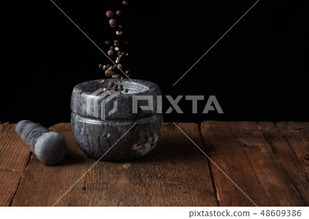 Pepper seeds fall into the mortar. Pepper seeds fall into the mortar. 48609386