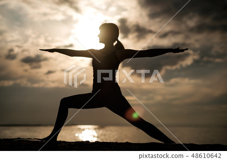 woman doing asana Virabhadrasana Warrior pose woman doing asana Virabhadrasana Warrior pose 48610642