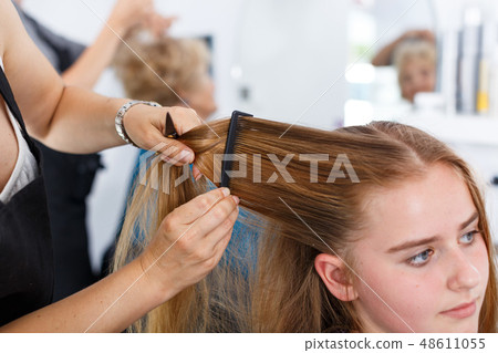 Hands of hairdresser making hairstyle for girl