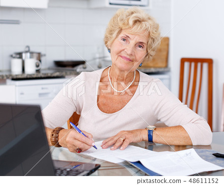 Mature woman filling up documents Mature woman filling up documents 48611152
