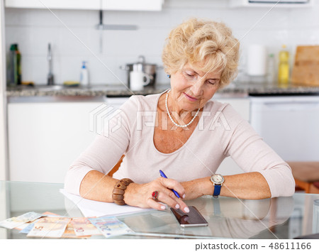 Woman counting her expenses using smartphone Woman counting her expenses using smartphone 48611166