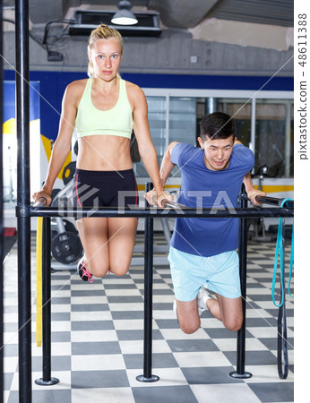 Couple exercising push-ups on bars Couple exercising push-ups on bars 48611388