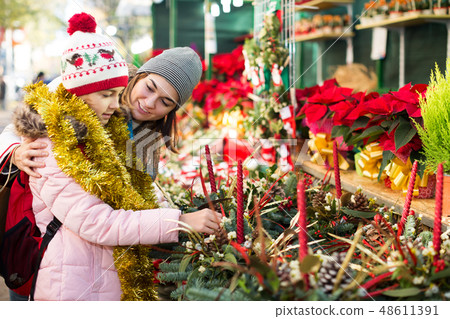 Girl with mother choosing floral decoration Girl with mother choosing floral decoration 48611391