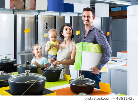 couple with two children picking new kitchenware in home appliances shop couple with two children picking new kitchenware in home appliances shop 48611423