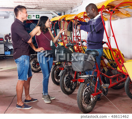 Dissatisfied African-American man driver of rickshaw talking with couple Dissatisfied African-American man driver of rickshaw talking with couple 48611462