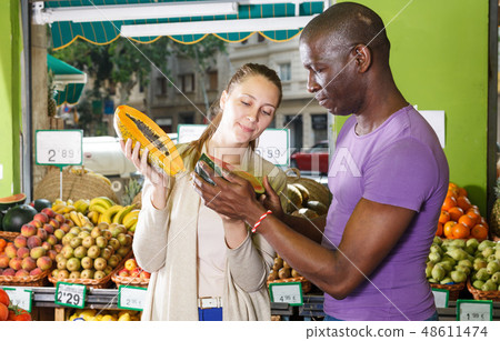 Smiling couple is choosing watermelon and melon Smiling couple is choosing watermelon and melon 48611474