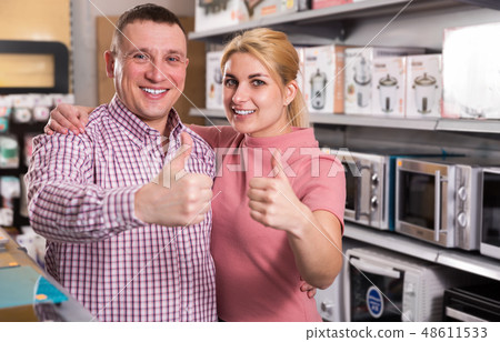 Smiling family holding thumbs up in section of household appliances Smiling family holding thumbs up in section of household appliances 48611533