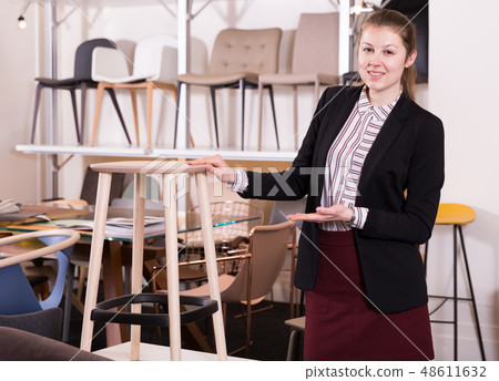 Salesgirl demonstrating bar stools l in salon 48611632