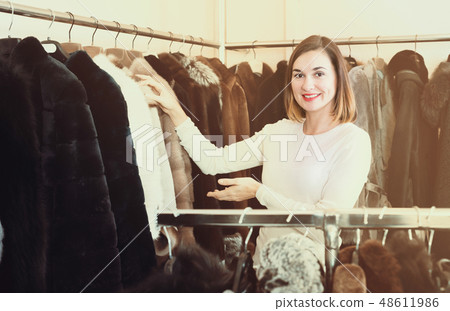 Beautiful girl deciding on warm fur coats Beautiful girl deciding on warm fur coats 48611986