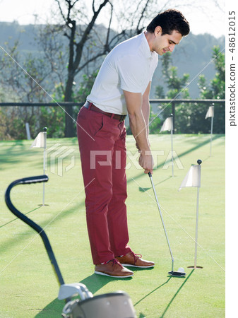 Man playing golf is going to hit ball at golf course Man playing golf is going to hit ball at golf course 48612015