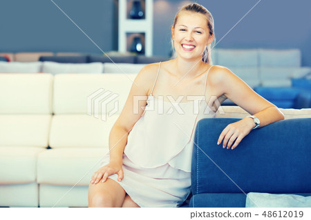Adult female touching sofa in the furniture store before the buying Adult female touching sofa in the furniture store before the buying 48612019