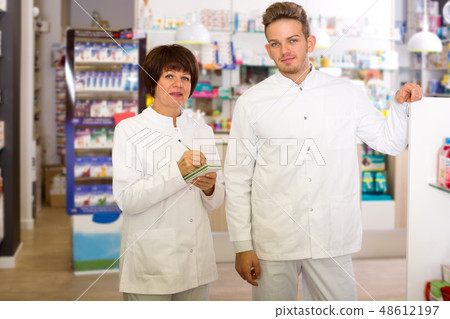 Pharmacist and pharmacy technician posing in drugstore 48612197