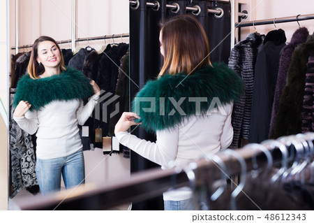 Smiling girl customer examining new fur neckpiece 48612343
