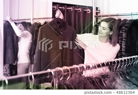 woman choosing sheepskin coat in women’s cloths store woman choosing sheepskin coat in women’s cloths store 48612364