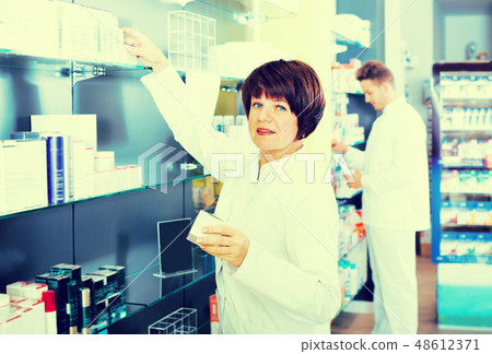 Pharmacist and pharmacy technician posing in drugstore Pharmacist and pharmacy technician posing in drugstore 48612371
