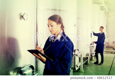 Female winery employee in uniform taking off data Female winery employee in uniform taking off data 48612517