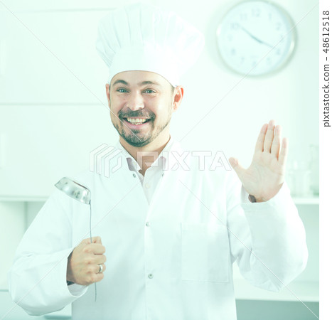 Positive young cook holding soup ladle Positive young cook holding soup ladle 48612518
